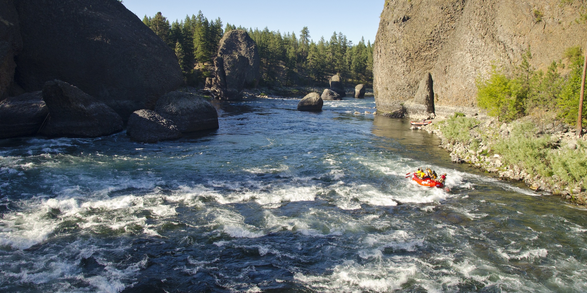 Raft approaching mild rapids in a rocky canyon, ideal for discussing different classes of whitewater difficulty.