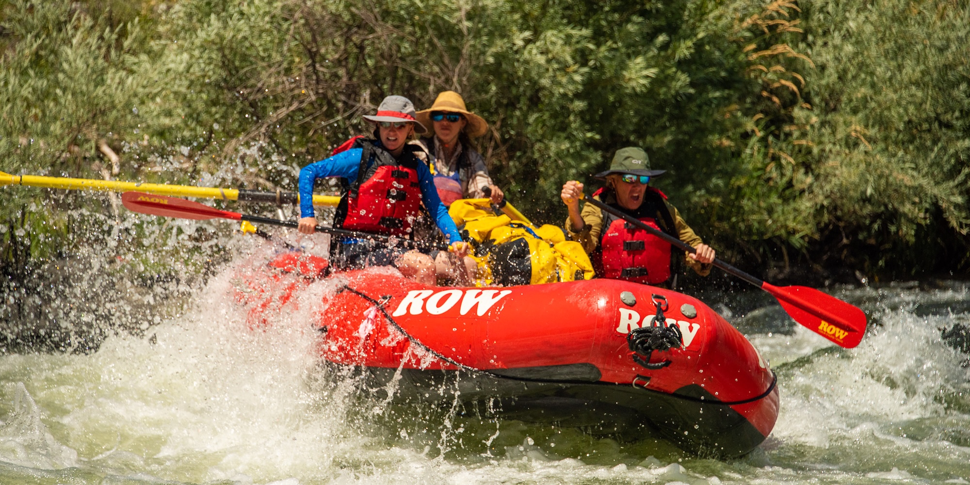 Guided whitewater rafting trip in Idaho with group paddling through waves and surrounded by lush riverbanks.