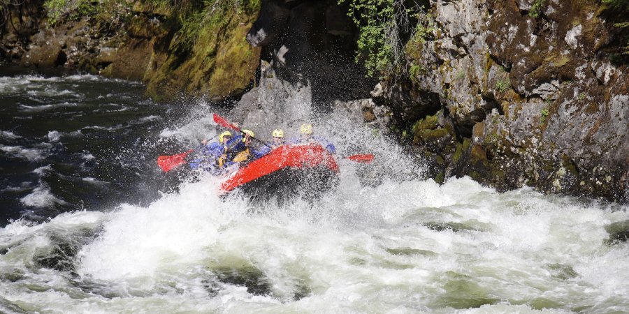A red raft disappearing inside of a massive whitewater wave in the beginning of a rapid. 